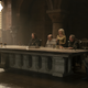King Viserys sits at the head of a long table with the members of his Small Council on the side.
